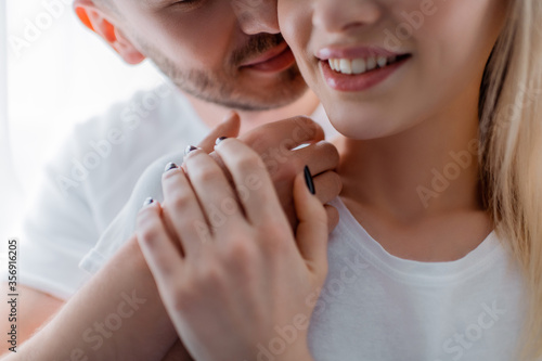 cropped view of man touching smiling girl at home