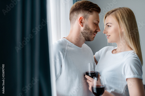 selective focus of handsome man and happy woman holding glasses with red wine © LIGHTFIELD STUDIOS