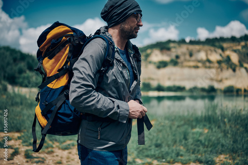 Young handsome man standing in nature with backpack on backs. Camping at weekend concept.