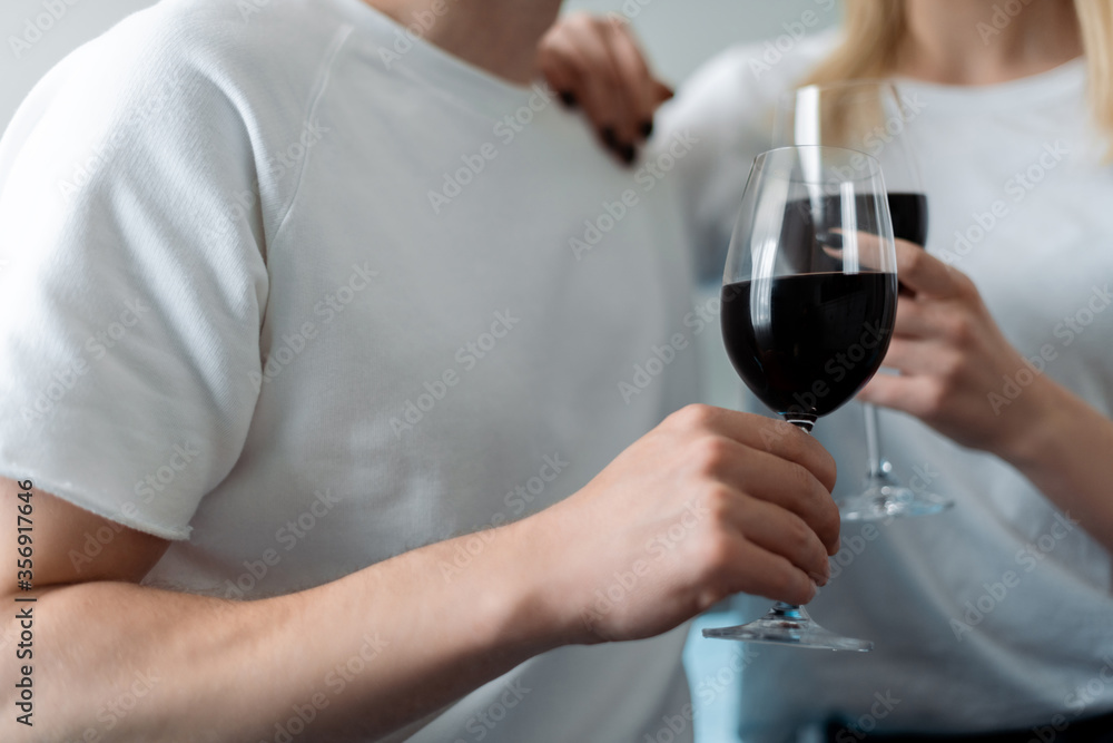 cropped view of man and woman holding glasses with red wine cropped view of man and woman holding glasses with red wine