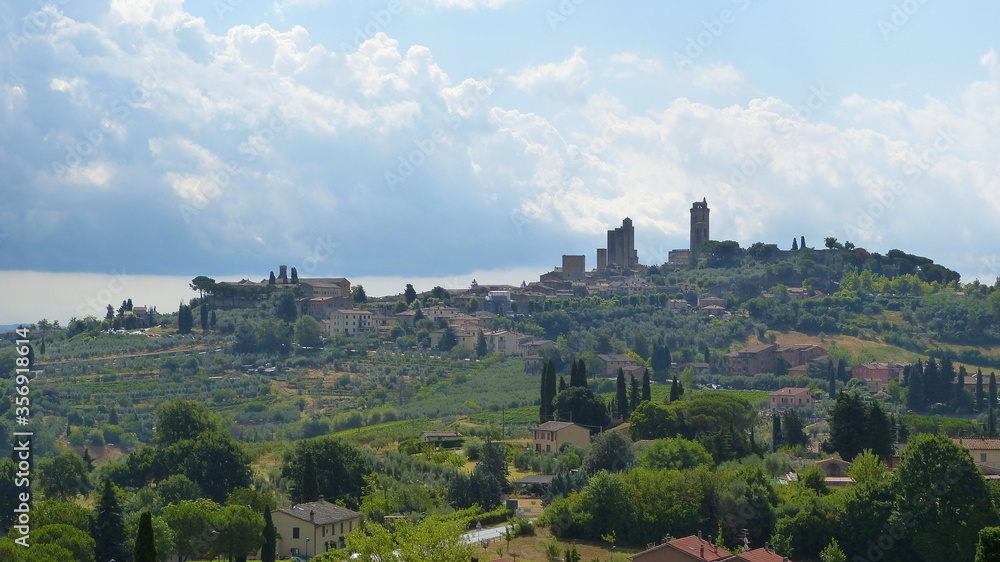 Blick auf San Gimignano in der Toskana im Sommer mit Hügellandschaft, Landgut, Olivenhainen und Zypressen