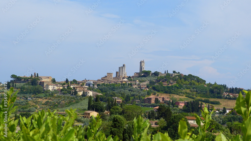 Blick auf San Gimignano in der Toskana im Sommer mit Hügellandschaft, Landgut, Olivenhainen und Zypressen
