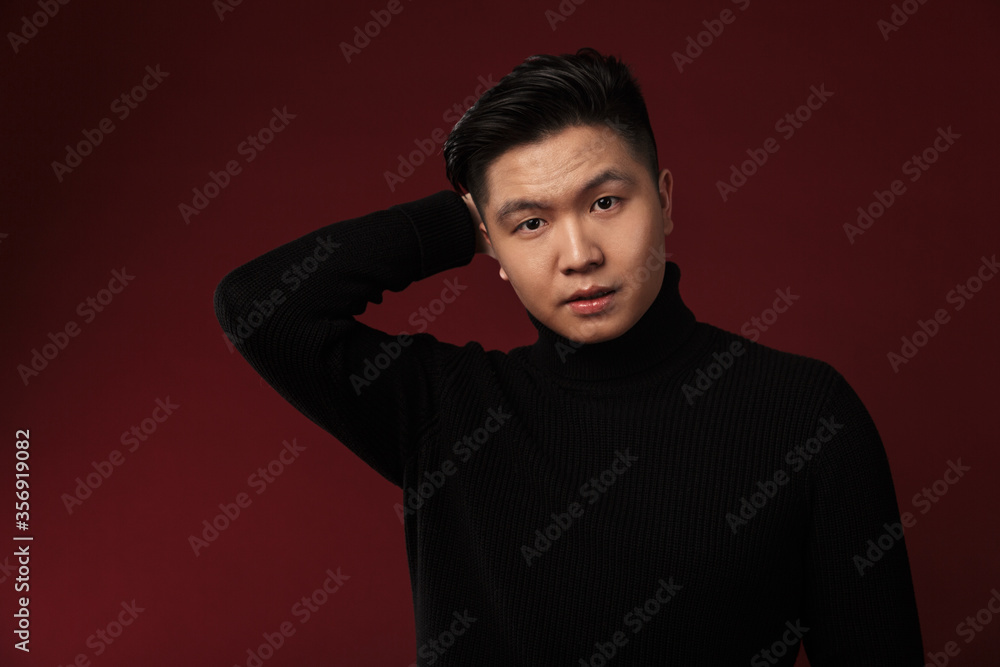 Fototapeta premium Image of confused asian man posing and looking at camera