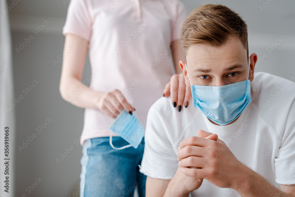 selective focus of woman touching man in medical mask at home selective focus of woman touching man in medical mask at home