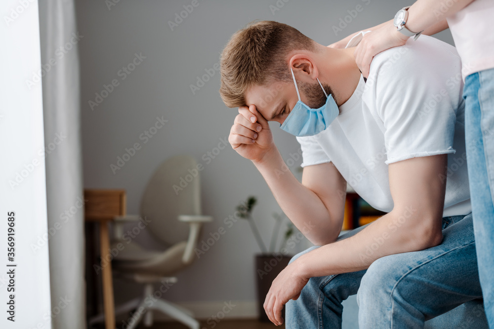 girl touching upset man in medical mask at home girl touching upset man in medical mask at home