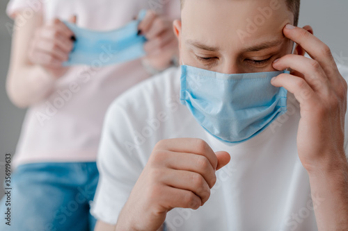 selective focus of man in medical mask touching face near woman