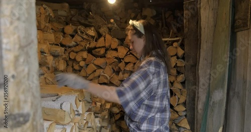Shed with Many Rows of Firewood. Tired Girl Brought Last Several Logs and Put them Exactly in Row. Stock of Firewood for Winter Season. Hard work. Village Labor. Birch Chocks. Easy Burns in Fireplace