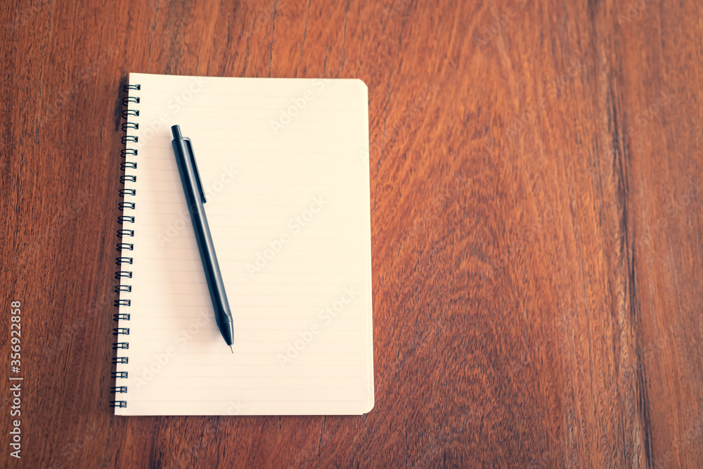 sketch notepad and a pen on wooden background with copy space. top view blank notebook and text. filter tone vintage style. sketch notepad and a pen on wooden background with copy space. top view blank notebook and text. filter tone vintage style.