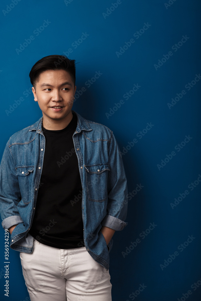 Fototapeta premium Image of pleased handsome asian man smiling and looking aside