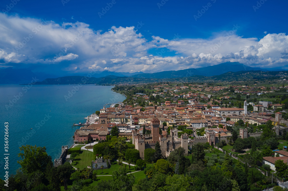 Lazise, Lake Garda, Italy. Aerial view of the historic part of Scaliger Castle of Lazise in the background cumulus clouds in the blue sky