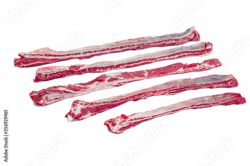 Raw flank steak, a cut of beef taken from the abdominal muscles or lower chest of the steer, ready to be cooked. On a cutting board with peppers aside, isolated on white background