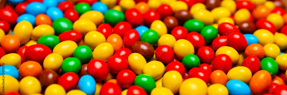 Image of colored round sweets. Background of small multicolored dragees. Closeup. Side vew. Banner. Image of colored round sweets. Background of small multicolored dragees. Closeup. Side vew. Banner.