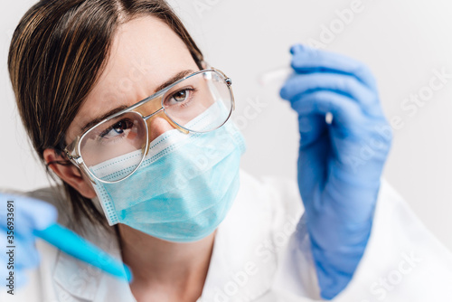 A blond medical or scientific researcher or doctor using looking at a clear solution in a laboratory