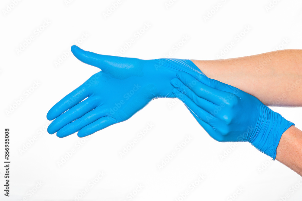 woman puts on her hand a nitrile blue glove with her other hand on a white background