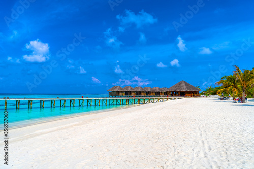 Wooden bridges leading to the huts on the shores of the tropical, warm sea. Maldives. Tourism concept. © lotosfoto