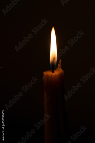 The candle flame is approaching the dark background in the night.