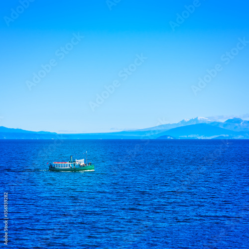 Tourist steamboat in the deep blur waters of Taupo lake with Ruapehu mountains in the background on a beautiful sunny day. North Island Volcanic Plateau, New Zealand photo