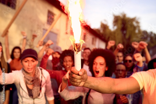 Close-up of an protester holding inflamed torch during public demonstrations.