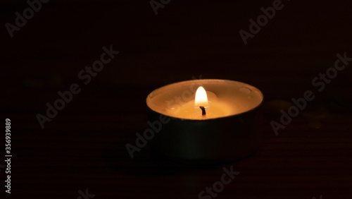 The candle flame is approaching the dark background in the night.