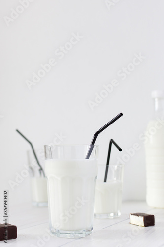 Fresh milk in a glass with black straws, chocolate candies with souffle, tasty healthy drink