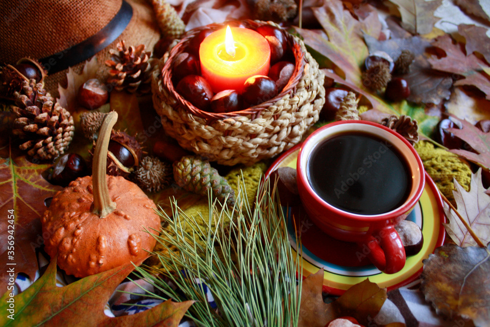 Autumn decoration, table with autumn leaves, cones, a pumpkin, a candle and a coffee cup, close up