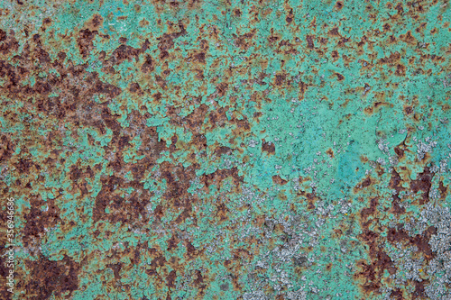 the surface of the old metal, pitted with rust, covered in old green paint © Kateryna
