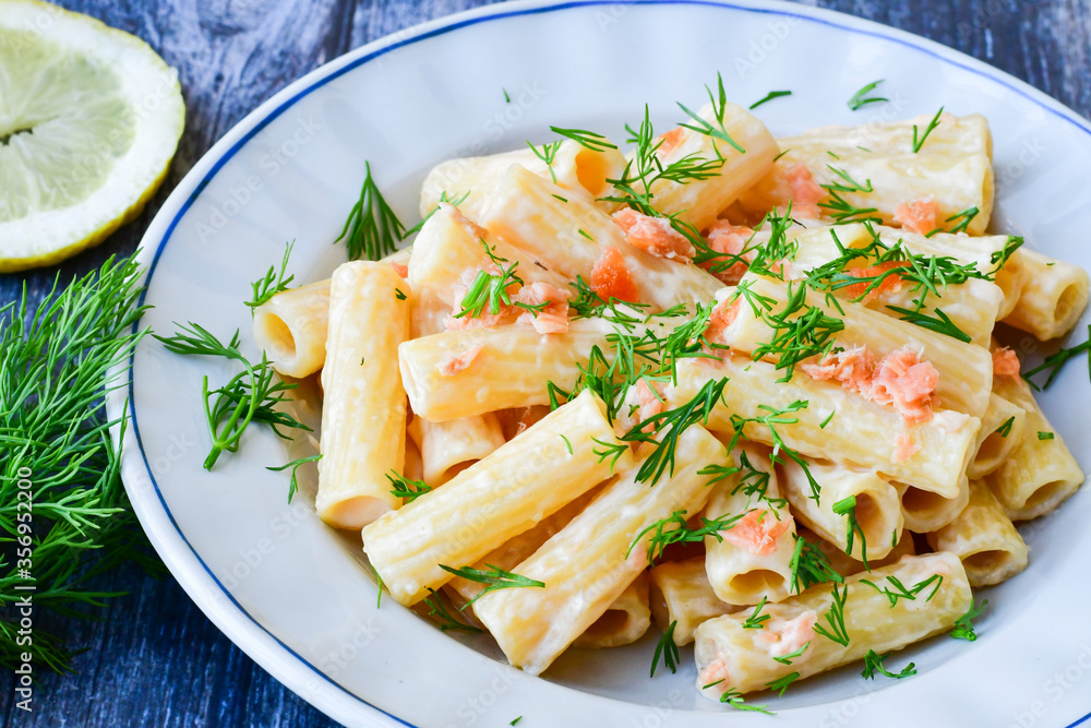 Italian home made macaroni pasta with smoked salmon , creamy sauce and fresh dill on wooden background Italian home made macaroni pasta with smoked salmon , creamy sauce and fresh dill on wooden background