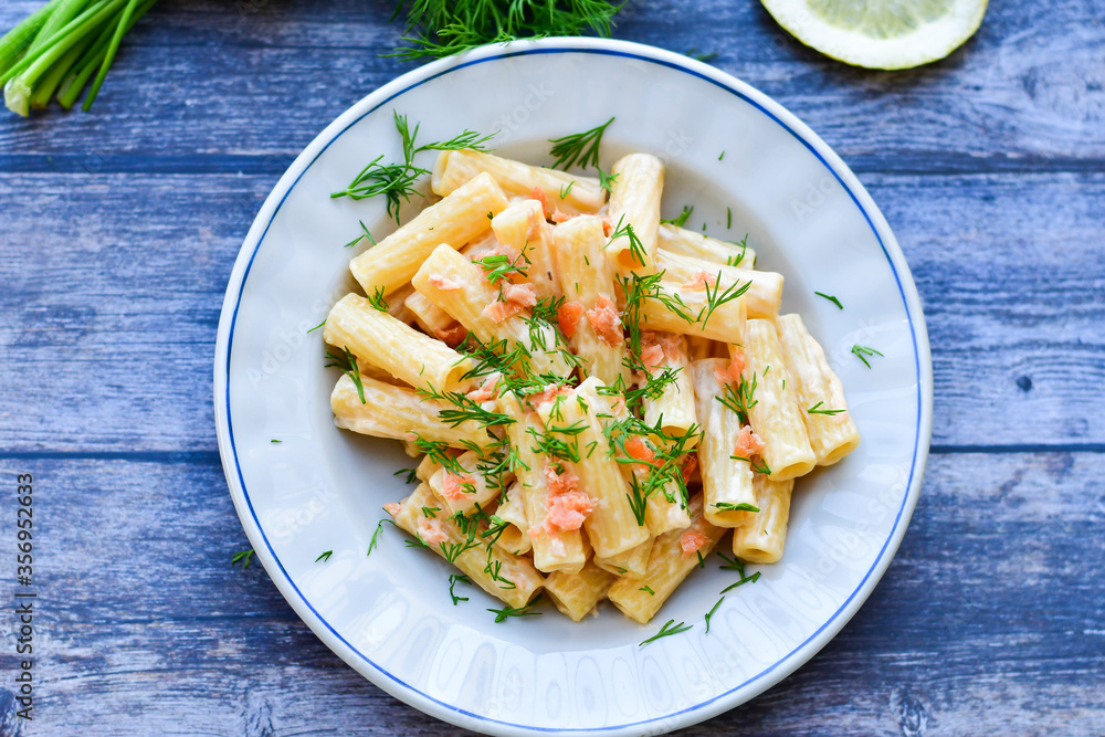 Italian home made macaroni pasta with smoked salmon , creamy sauce and fresh dill on wooden background Italian home made macaroni pasta with smoked salmon , creamy sauce and fresh dill on wooden background