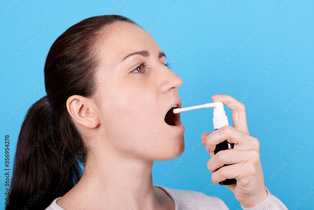 Portrait of a brunette girl using throat spray. Portrait of a brunette girl using throat spray.
