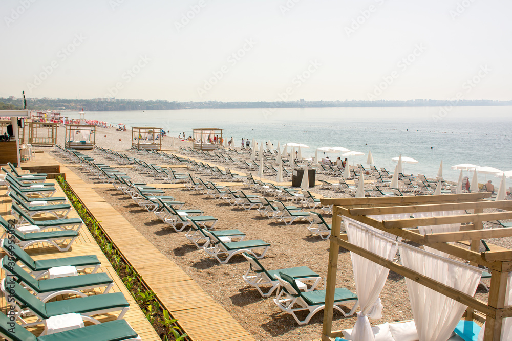 Obraz premium The tourist season is open, very few tourists have arrived, there are many empty sunbeds and beach chairs. Konyaalti Beach, Antalya, Turkey.