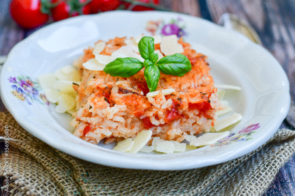 Home made italian oven baked tomato risotto with a fresh leaf of basil and parmesan cheese Home made italian oven baked tomato risotto with a fresh leaf of basil and parmesan cheese