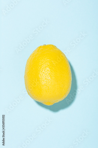 Bright yellow lemon on blue background. Minimal styled summer concept.