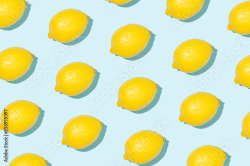 Pattern made of bright yellow lemons in sunlight on blue background. Minimal styled summer concept. © Olga Zarytska