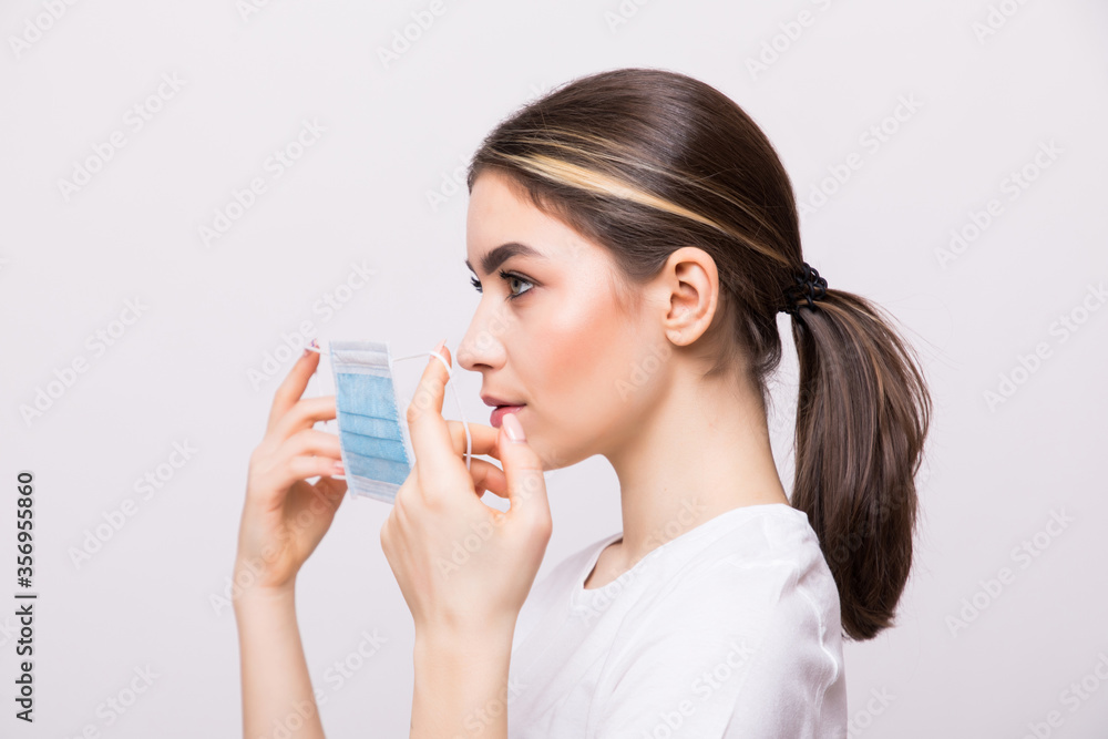 Portrait of a young girl wearing medical mask isolated on a white wall background. Portrait of a young girl wearing medical mask isolated on a white wall background.