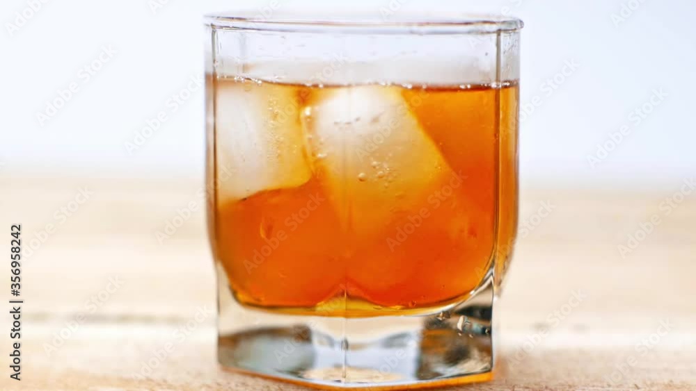 glass of whiskey with ice cubes on wooden table isolated on white glass of whiskey with ice cubes on wooden table isolated on white