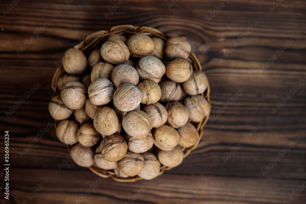 A basket full of inshell walnuts on a wooden background. View from above. Natural, healthy product. Space for text.