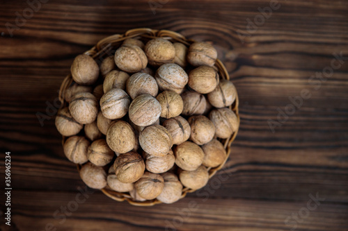 A basket full of inshell walnuts on a wooden background. View from above. Natural, healthy product. Space for text.