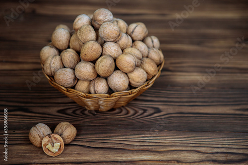 A basket full of inshell walnuts on a wooden background. Natural, healthy product. Space for text.