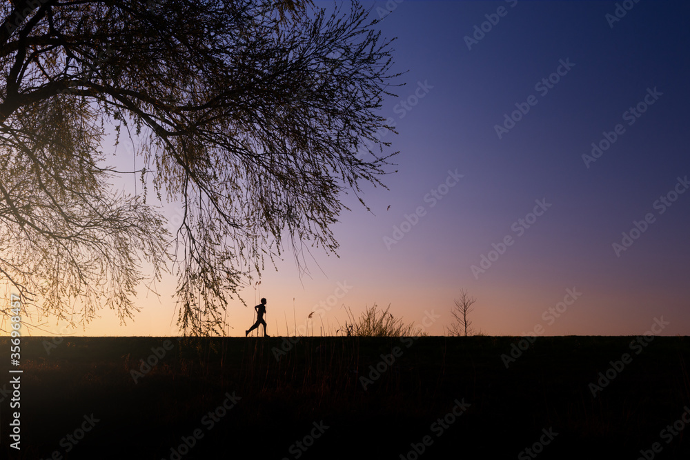 Boy or male man runs at sunset to stay healthy, healthy lifestyle, sport concept, calm and warm evening Landscape with blue and orange colors