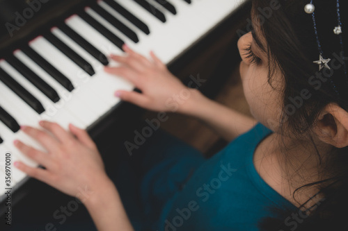School age British Indian girl practices a piano at home. 