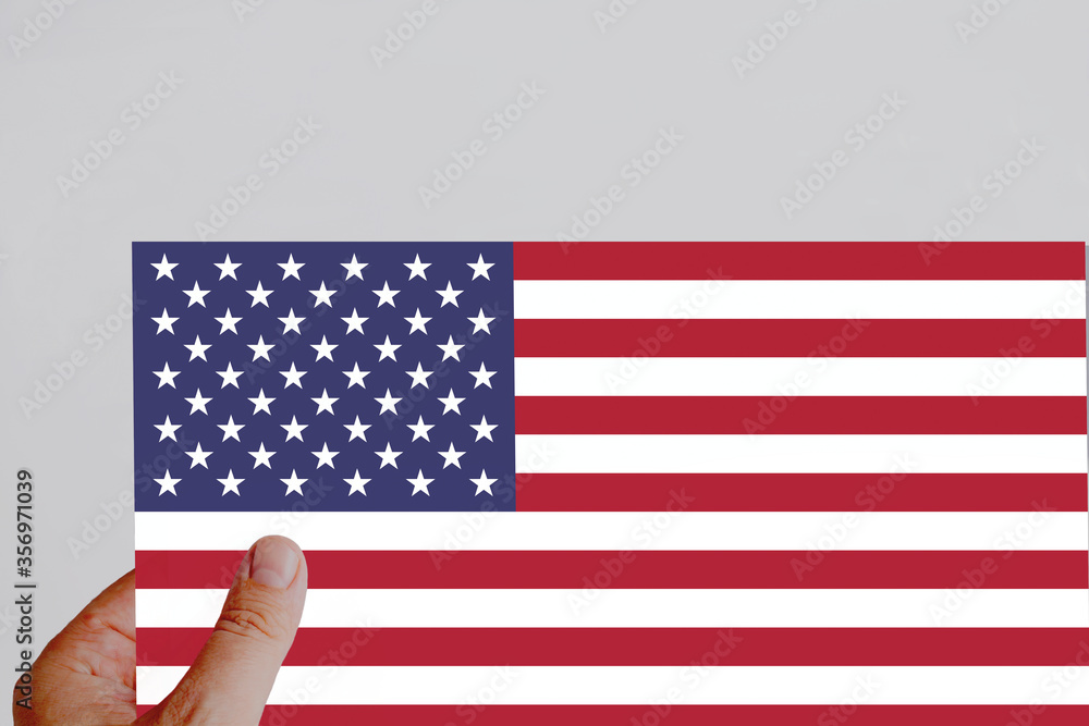 Male hand holding the American flag paper flag.
White background.National flag.