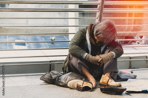 Φωτογραφία Homeless man is sitting down on walkway in town.