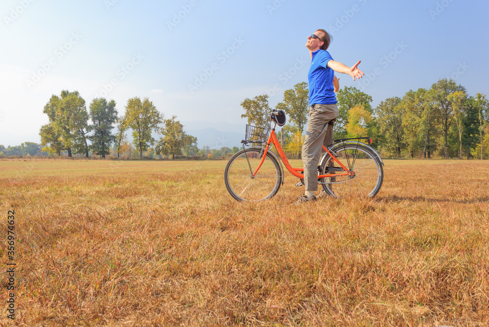 a man exercises on a bicycle /a healthy lifestyle of a fifty-years-old man practicing cycling in a park a man exercises on a bicycle /a healthy lifestyle of a fifty-years-old man practicing cycling in a park