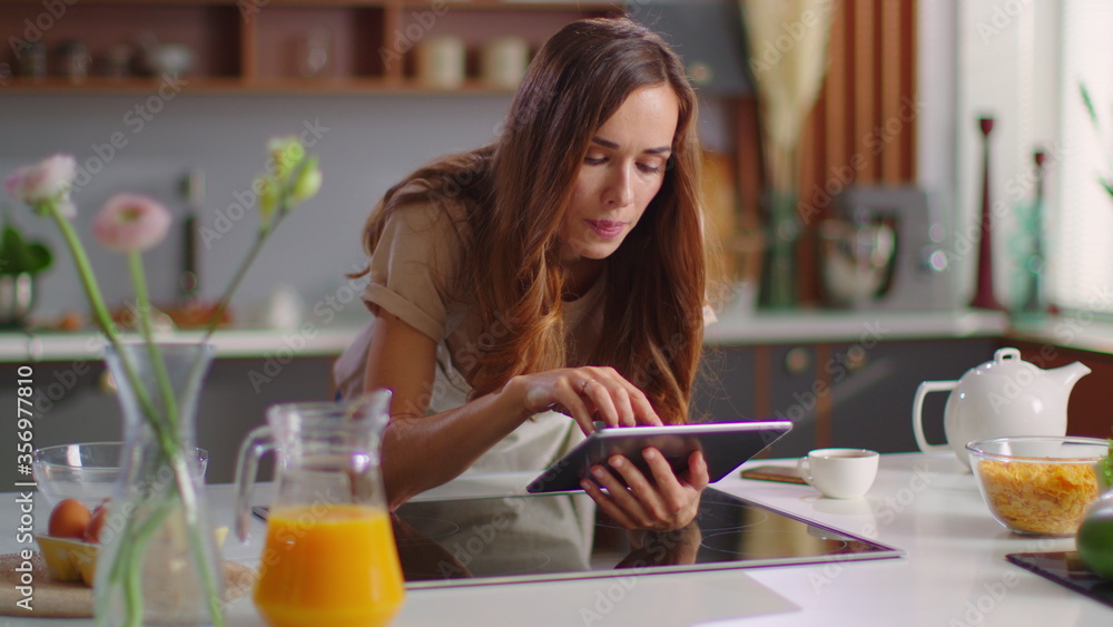 Attractive woman using digital tablet on kitchen. Girl browsing internet on pad Attractive woman using digital tablet on kitchen. Girl browsing internet on pad