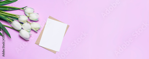 White tulip flowers with gift boxes and empty paper with copyspace on lilac background