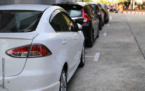 Closeup of rear, back side of white car with  other cars parking in outdoor parking area. © Amphon