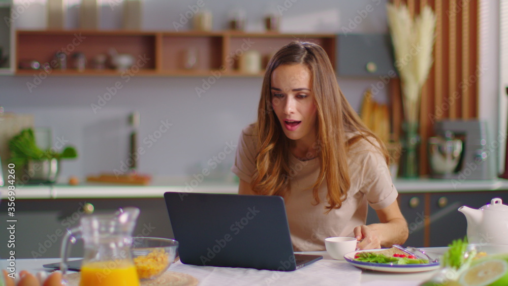 Shocked businesswoman getting good news on laptop screen at home office