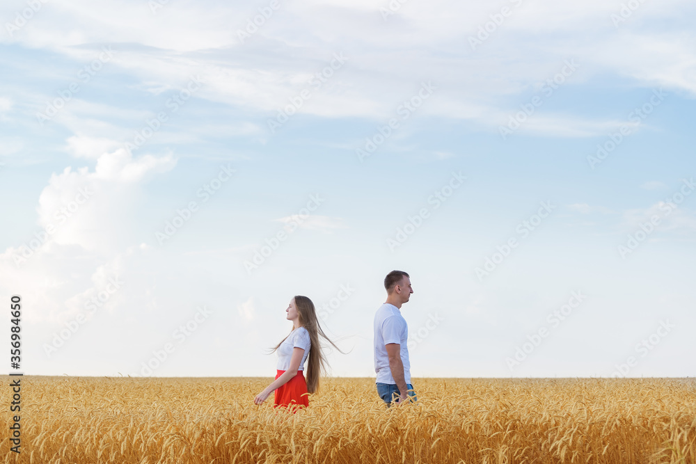 Man and woman standing back to each other in wheat field. Quarrel and misunderstanding in family