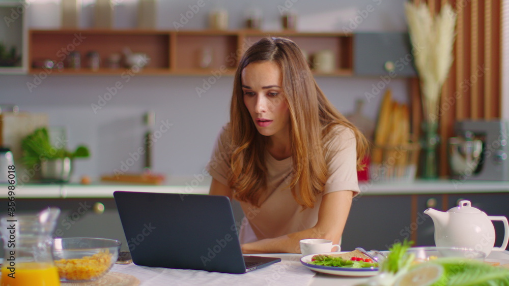Businesswoman using laptop at home office. Woman working on laptop at kitchen