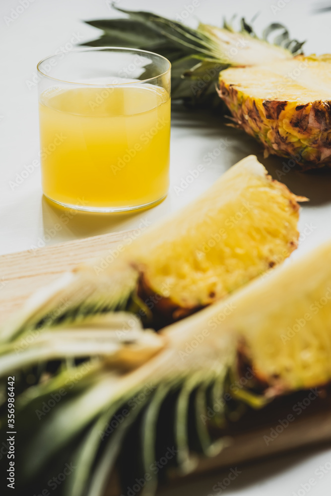 selective focus of fresh pineapple juice near cut delicious fruit on cutting board on white background selective focus of fresh pineapple juice near cut delicious fruit on cutting board on white background